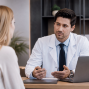 Cirurgião plástico conversa com paciente durante consulta em consultório moderno