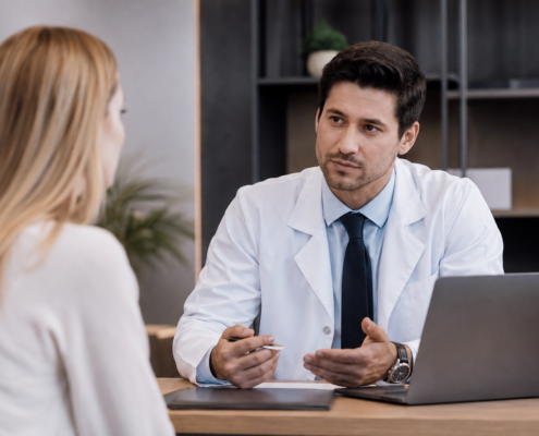 Cirurgião plástico conversa com paciente durante consulta em consultório moderno